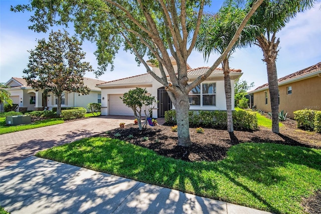 view of front of home with an attached garage, a tile roof, stucco siding, a front lawn, and decorative driveway