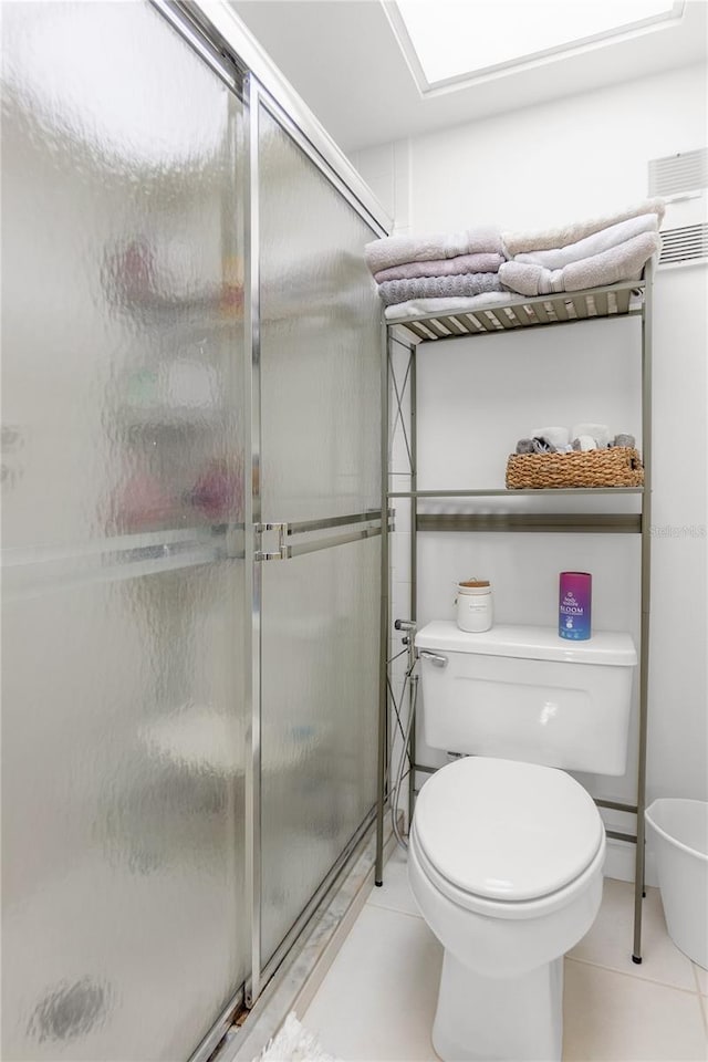 bathroom featuring tile patterned flooring, toilet, and a stall shower
