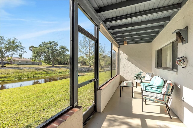 sunroom with beam ceiling and a water view