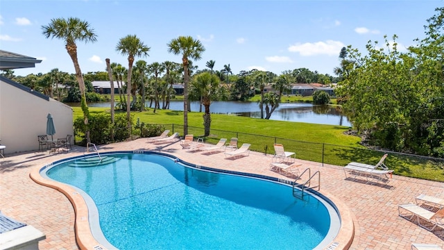 pool with a water view, a patio, a yard, and fence