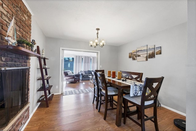 4243 Maceachen Blvd, Sarasota, FL 34233 - dining area with a chandelier, a brick fireplace, baseboards, and wood finished floors