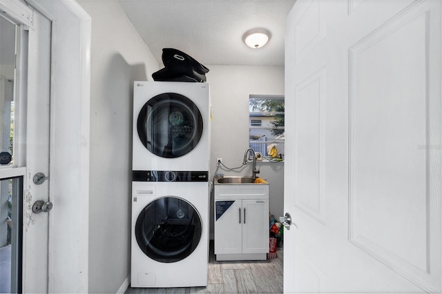 4243 Maceachen Blvd, Sarasota, FL 34233 - laundry room featuring stacked washer / dryer, light wood finished floors, a sink, and cabinet space