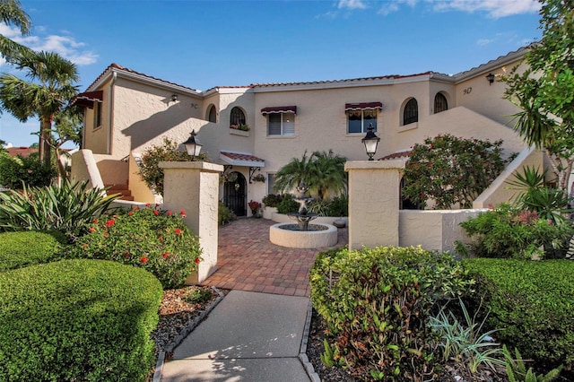 mediterranean / spanish house with a tile roof, stucco siding, and decorative driveway