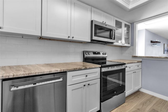 kitchen featuring stainless steel appliances, light wood-style flooring, white cabinets, and glass insert cabinets