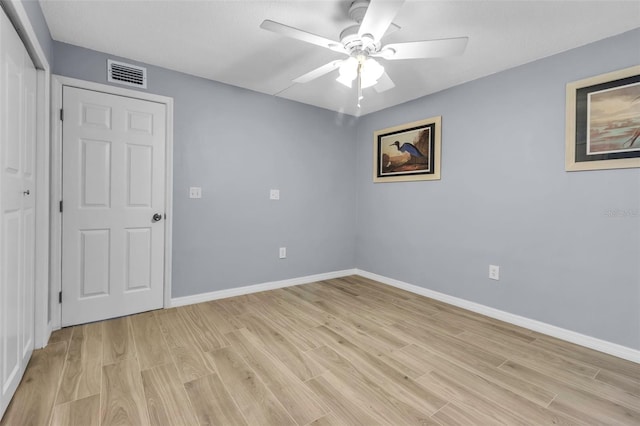 empty room with light wood-style floors, a ceiling fan, and baseboards