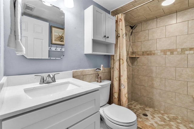 full bath featuring vanity, a stall shower, toilet, and tile walls