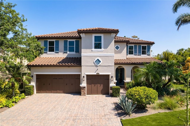 mediterranean / spanish home featuring a garage, stucco siding, decorative driveway, and a tiled roof