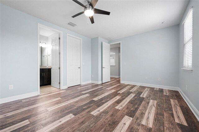 unfurnished bedroom featuring connected bathroom, visible vents, wood finished floors, and baseboards