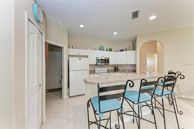 1631 Madison Ave, North Port, FL 34286 - kitchen with a kitchen breakfast bar, white appliances, light countertops, white cabinets, and visible vents