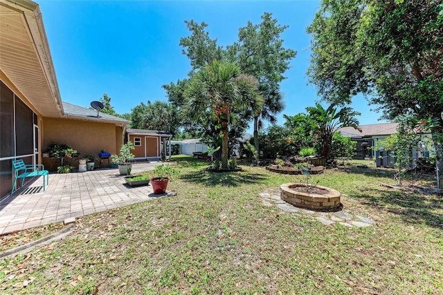 1631 Madison Ave, North Port, FL 34286 - view of yard with a sunroom, an outdoor structure, an outdoor fire pit, a patio area, and fence