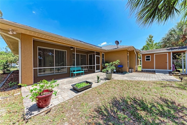 1631 Madison Ave, North Port, FL 34286 - rear view of house featuring a patio, stucco siding, an outdoor structure, and a sunroom