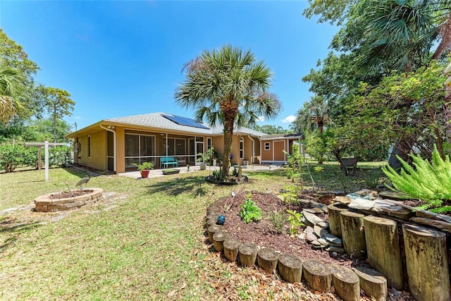 1631 Madison Ave, North Port, FL 34286 - rear view of property featuring a fire pit, a sunroom, roof mounted solar panels, a yard, and stucco siding