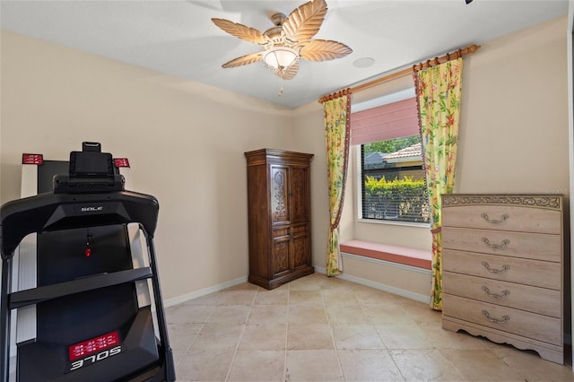 workout room featuring light tile patterned flooring, a ceiling fan, and baseboards