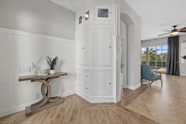 hallway featuring wainscoting, baseboards, and ornamental molding