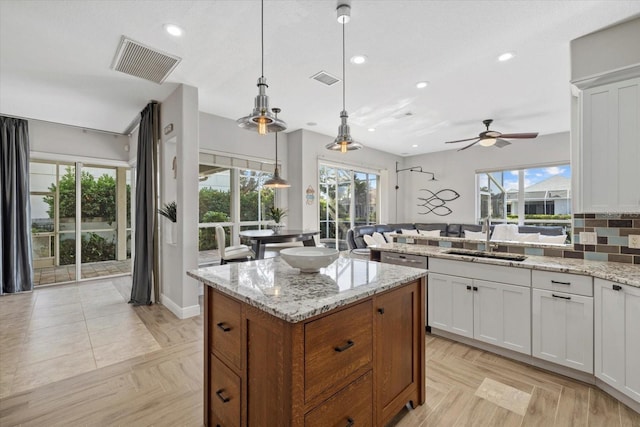 kitchen with a ceiling fan, visible vents, a center island, a sink, and open floor plan
