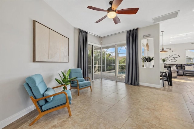 living area with visible vents, baseboards, and ceiling fan
