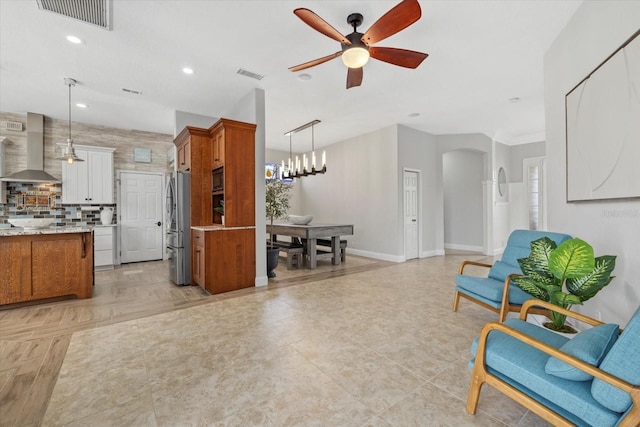 interior space with arched walkways, ceiling fan with notable chandelier, baseboards, and visible vents