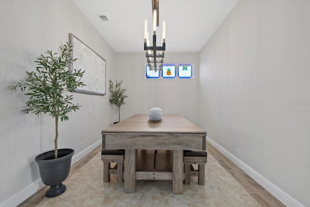 dining room with visible vents, baseboards, light wood finished floors, and a chandelier