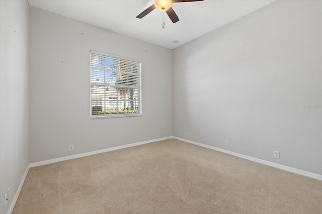 carpeted spare room featuring baseboards and a ceiling fan