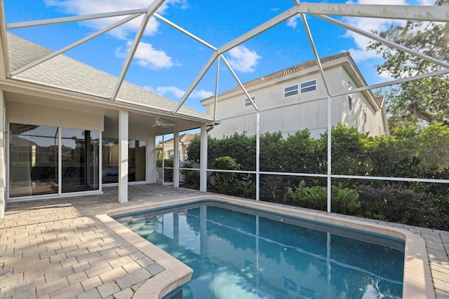 pool featuring a patio area, glass enclosure, and ceiling fan