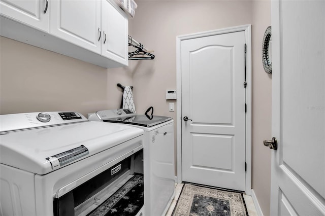 clothes washing area featuring cabinet space, washing machine and clothes dryer, and baseboards