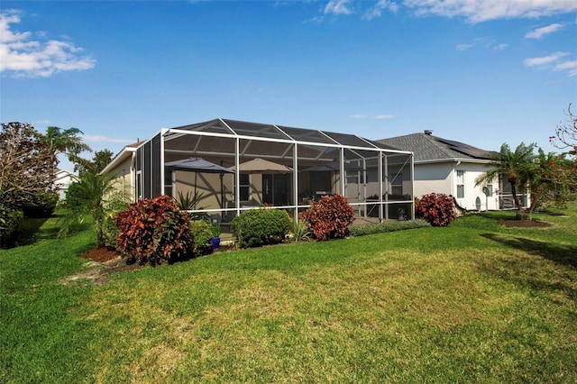 rear view of house with a lawn and glass enclosure