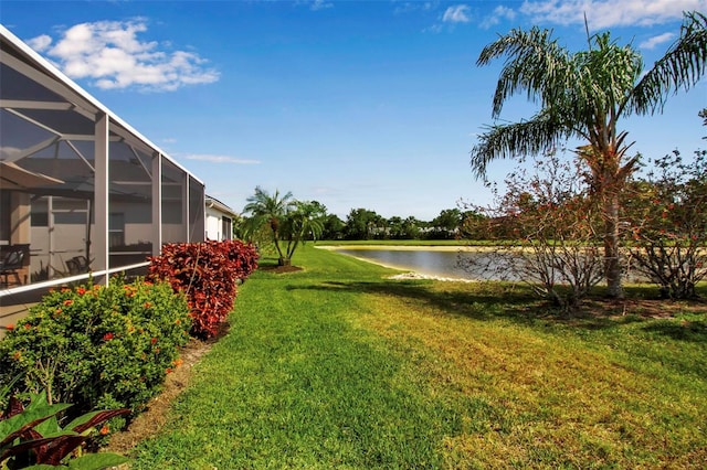 view of grassy yard with a water view and glass enclosure