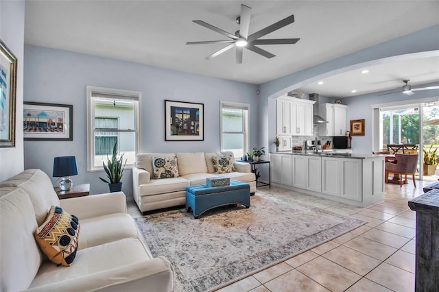 living area with a ceiling fan, recessed lighting, light tile patterned floors, and arched walkways