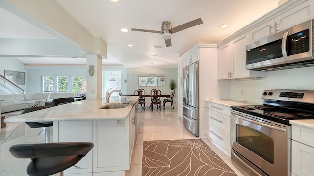 5324 Siesta Ct, Sarasota, FL 34242 - kitchen with white cabinetry, a sink, stainless steel appliances, open floor plan, and a breakfast bar area