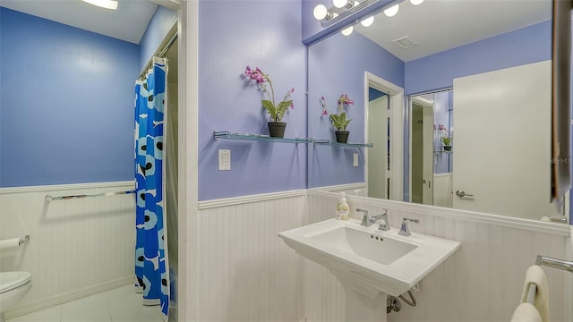 5324 Siesta Ct, Sarasota, FL 34242 - bathroom with toilet, a wainscoted wall, a shower with shower curtain, and tile patterned flooring
