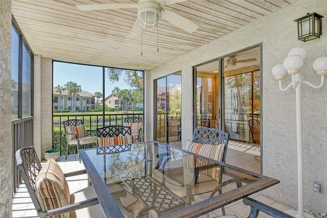 sunroom / solarium featuring a residential view, a ceiling fan, and outdoor dining area