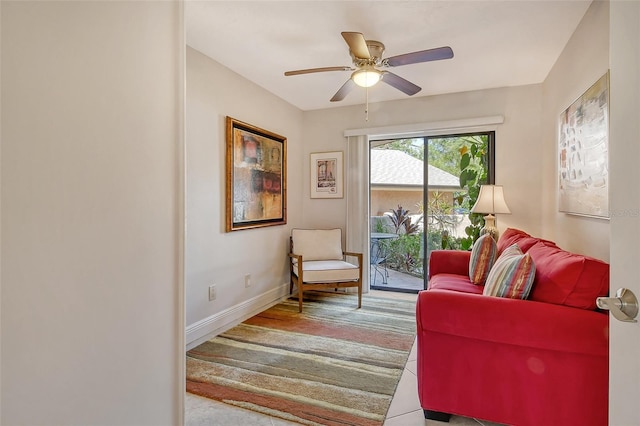living area with baseboards and a ceiling fan