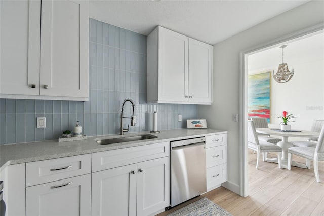 kitchen featuring light countertops, a sink, tasteful backsplash, white cabinetry, and dishwasher