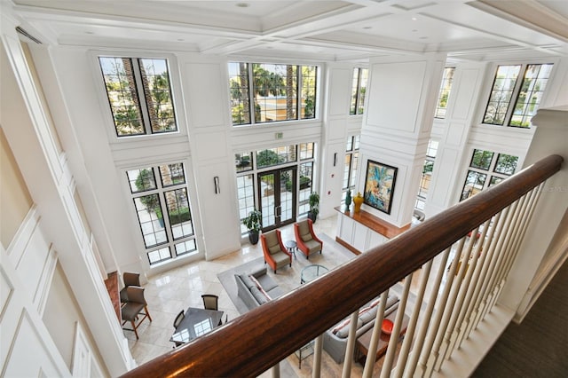 interior space featuring a high ceiling, beam ceiling, coffered ceiling, and a decorative wall