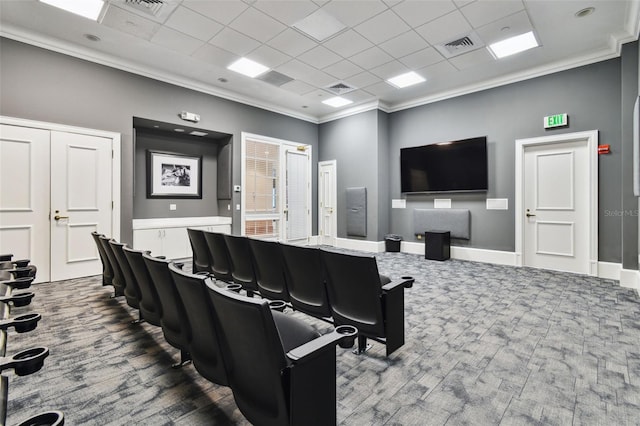 cinema room with dark colored carpet, visible vents, ornamental molding, and a drop ceiling