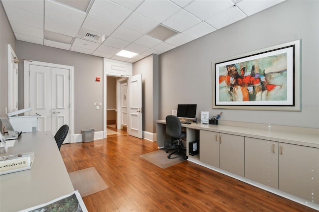 office space with visible vents, wood finished floors, and a drop ceiling