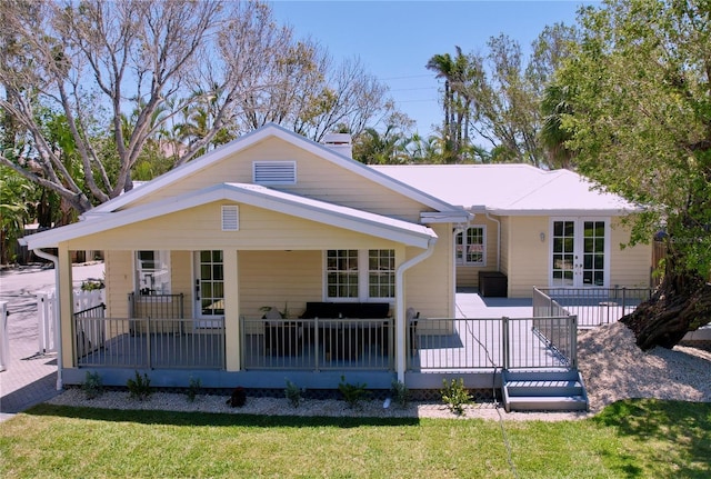 back of house with french doors, a lawn, and covered porch