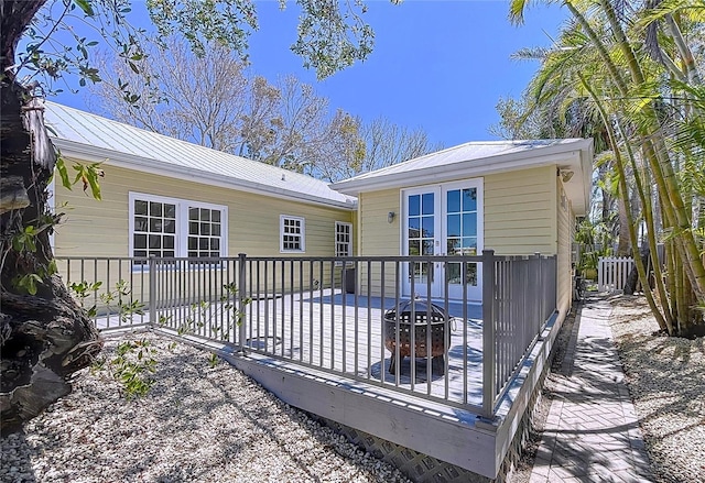 rear view of house featuring metal roof, a deck, and fence