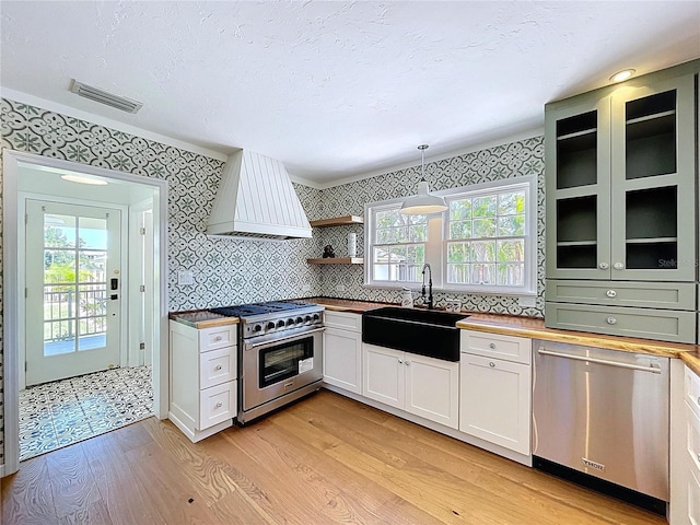 kitchen with a sink, appliances with stainless steel finishes, light wood-style floors, and wallpapered walls