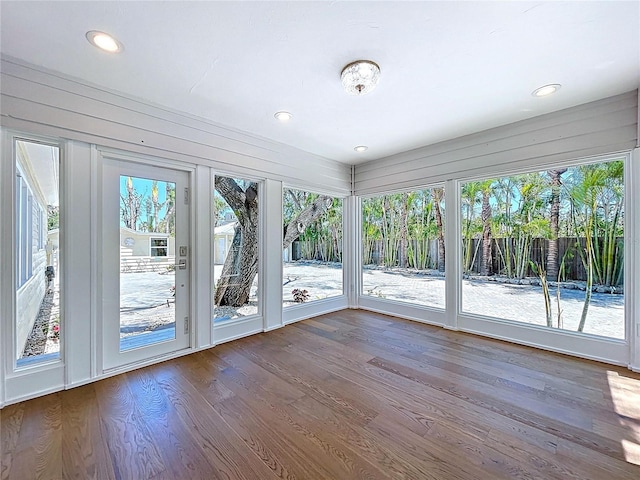 unfurnished sunroom with recessed lighting, a deck, and wood finished floors
