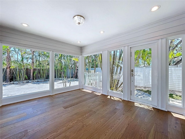 unfurnished sunroom featuring a healthy amount of sunlight, wood finished floors, a deck, and recessed lighting