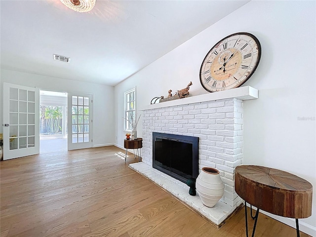living room with baseboards, wood finished floors, a brick fireplace, and visible vents