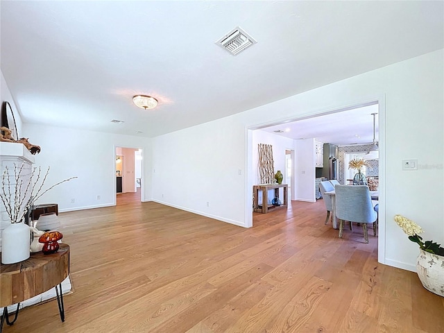 living area with light wood finished floors, visible vents, and baseboards