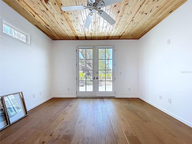 empty room featuring wood ceiling, french doors, baseboards, and a ceiling fan
