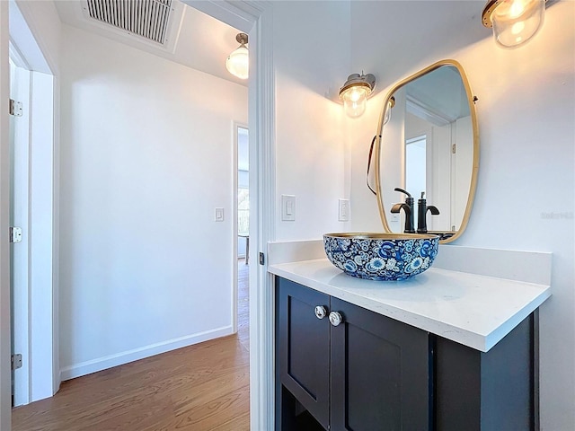 bathroom featuring vanity, visible vents, baseboards, and wood finished floors