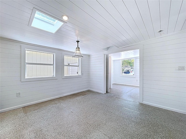 unfurnished dining area featuring wooden walls, wood ceiling, and a skylight