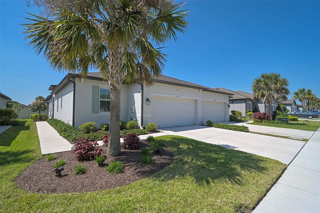 view of front of house featuring a garage, a front lawn, stucco siding, and concrete driveway
