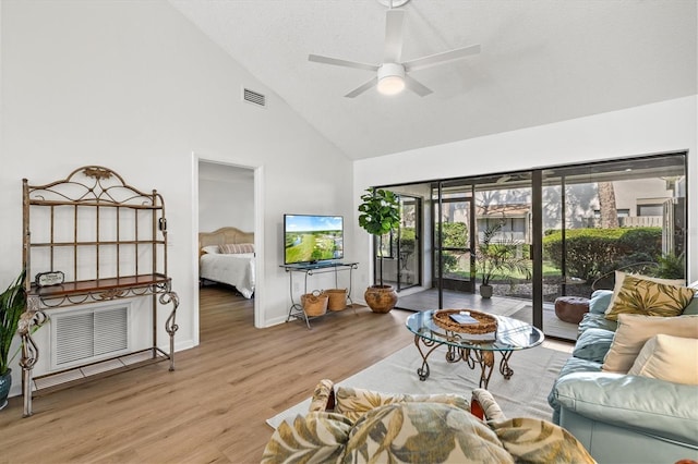 living room featuring light wood-type flooring, high vaulted ceiling, ceiling fan, and visible vents