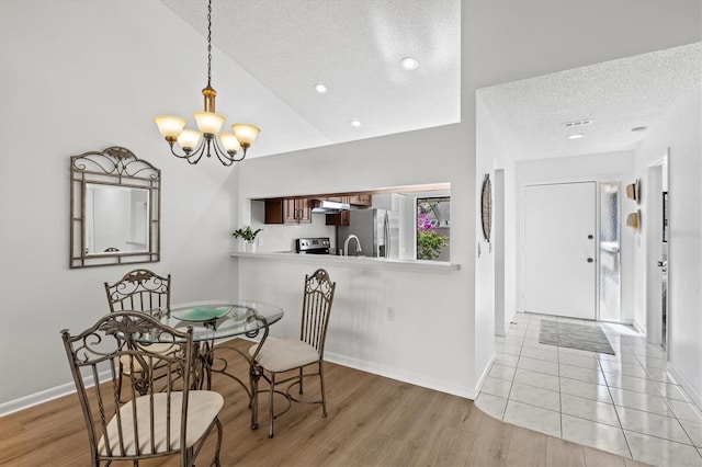 dining room with baseboards, light wood finished floors, an inviting chandelier, and a textured ceiling