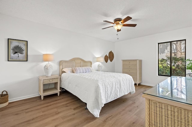bedroom featuring baseboards, light wood finished floors, and ceiling fan